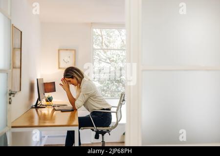 donna d'affari che ha mal di testa nel suo ufficio. Donna d'affari affaticata, affaticata dal lavoro mentre si trova di fronte a un notebook. Foto Stock