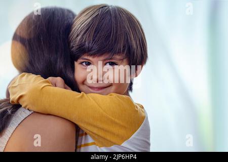 L'amore più bello e duraturo che c'è: Un adorabile ragazzino che abbraccia affettuosamente la madre a casa. Foto Stock