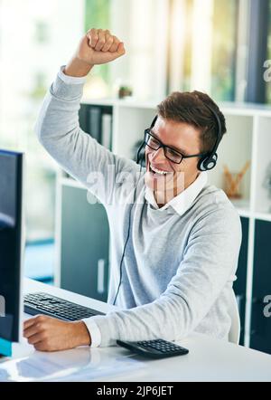 Indovinate chi ha appena raddoppiato l'obiettivo di vendita. Un giovane operatore del call center si fa tifoso mentre lavora in ufficio. Foto Stock