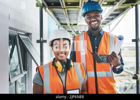 Ingegneri afro-americani felici e orgogliosi in un cantiere di costruzione che progetta un edificio insieme. Ritratto di giovani imprenditori in piedi in un appartamento Foto Stock