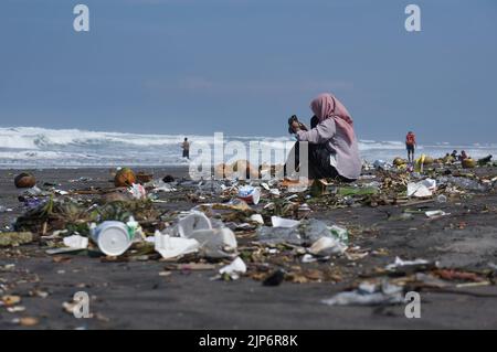 I turisti giocano sulla sporca spiaggia di Parangkusumo a Yogyakarta, Indonesia Foto Stock