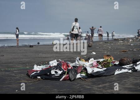 I turisti giocano sulla sporca spiaggia di Parangkusumo a Yogyakarta, Indonesia Foto Stock