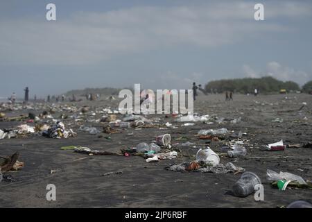 I turisti giocano sulla sporca spiaggia di Parangkusumo a Yogyakarta, Indonesia Foto Stock