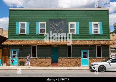 Una donna passa davanti al Green Frog Inn a Fort Wayne, Indiana, USA Foto Stock