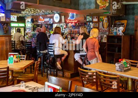 Una donna passa accanto ai patroni del bar nel Green Frog Inn a Fort Wayne, Indiana, USA. Foto Stock