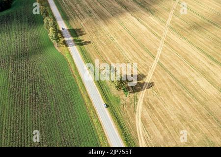 paesaggio rurale autunnale con auto su una strada di campagna tra i campi agricoli. vista aerea dal drone volante. Foto Stock