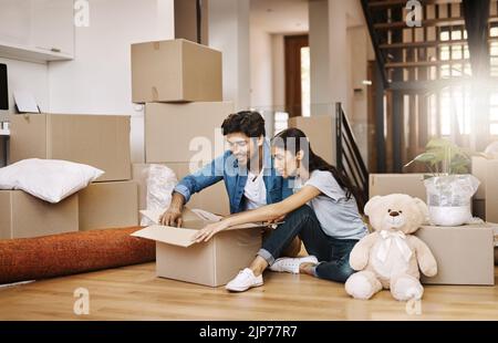 Theyve ha ottenuto mólto da disimballare. Colpo completo di una giovane coppia affettuosa che disimballa le loro scatole il giorno in movimento. Foto Stock