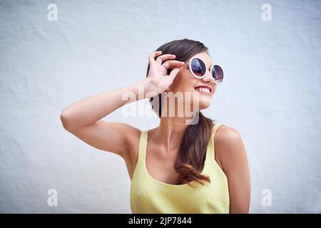 Gli occhiali sono adatti a te. Studio di una giovane donna allegra che indossa occhiali da sole mentre si posa su uno sfondo grigio. Foto Stock