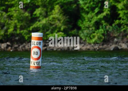 Una boa che galleggia sulla superficie di un lago dice 'slow' e 'no wake', indicando che le barche dovrebbero entrare lentamente nella zona. Foto Stock