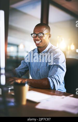 Niente migliora il business come mettere nelle ore. Un giovane uomo d'affari che usa un computer durante la notte tarda in un ufficio moderno. Foto Stock