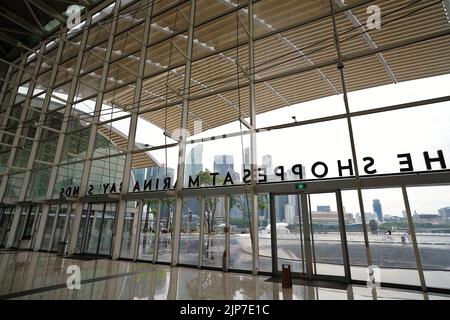 Interno dello Shoppes at Marina Bay Sands, con vedute panoramiche dello skyline di Singapore attraverso la baia Foto Stock