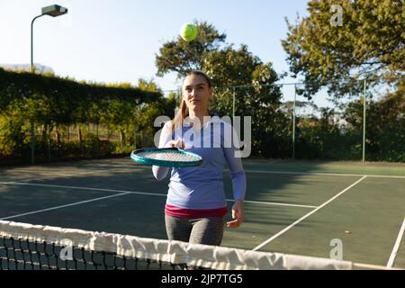 Donna caucasica che gioca a tennis pallina rimbalzante su racchetta sul campo da tennis all'aperto Foto Stock