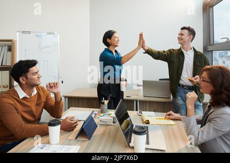I membri entusiasti del team aziendale si sono regalati cinque anni dopo aver completato il lavoro su un progetto di grandi dimensioni Foto Stock