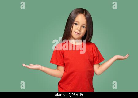 Ragazza sorpresa con braccia spalmato isolato su sfondo verde Foto Stock