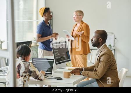 Team di programmatori che scrivono codici di nuovo software su computer e discutono di progetto online in team durante la riunione Foto Stock