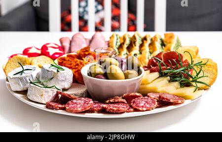 La cucina italiana propone piatti invitanti: Gustosi con peperoni, prosciutto crudo, formaggio brie, salumi, marmellata e focaccia abbinati a salumi e olive Foto Stock