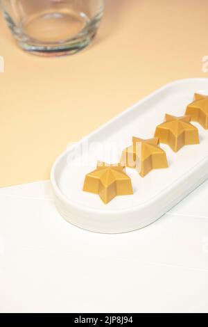 Cioccolato fatto a mano a forma di stella su un piatto bianco. Cioccolatieri fatti a mano. Foto Stock
