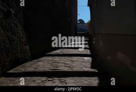 Stradina ciottolata stretta di Sorrento vicino a Marina Grande scatto suggestivo con il sole che cade sulla strada e ombra edifici circostanti. Foto Stock