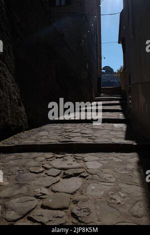 Stradina ciottolata stretta di Sorrento vicino a Marina Grande scatto suggestivo con il sole che cade sulla strada e ombra edifici circostanti. Foto Stock