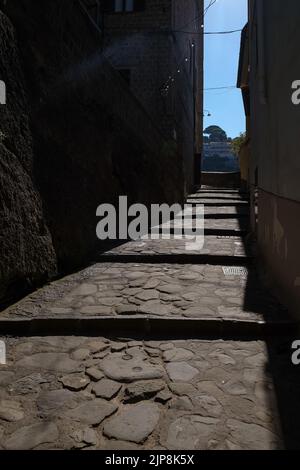 Stradina ciottolata stretta di Sorrento vicino a Marina Grande scatto suggestivo con il sole che cade sulla strada e ombra edifici circostanti. Foto Stock