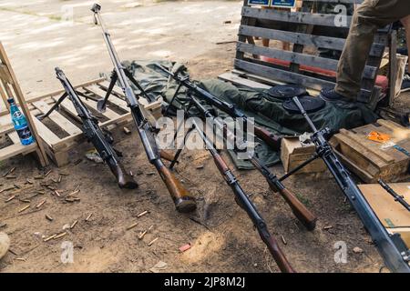 Stoccaggio di varie pistole e fucili sul campo di tiro. Munizioni e armi per attrezzature militari. Scatto orizzontale. Foto di alta qualità Foto Stock
