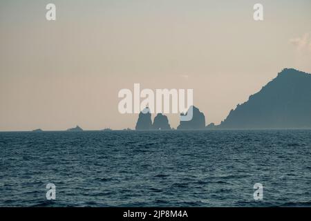 Capri faraglioni Wave erosione formazioni rocciose stagni dell'isola di Capri Italia nella baia di Napoli vista nella nebbia marina con barche da diporto. Foto Stock