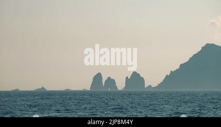 Capri faraglioni Wave erosione formazioni rocciose stagni dell'isola di Capri Italia nella baia di Napoli vista nella nebbia marina con barche da diporto. Foto Stock