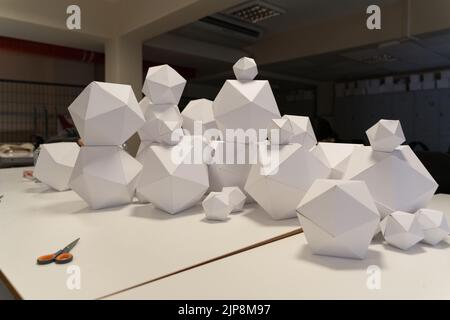 Sul tavolo sono presenti figure geometriche in carta con molte superfici. Foto Stock