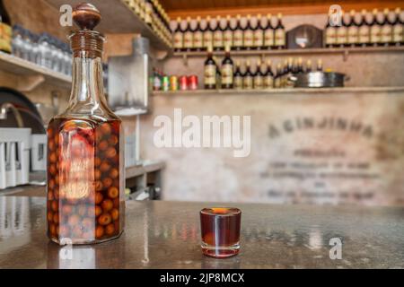 Bottiglia e bicchierino con un liquore di ciliegia tradizionale Ginjinha primo piano a Lisbona, Portogallo. Foto Stock