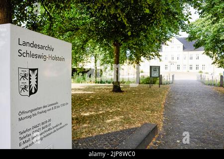 16 agosto 2022, Schleswig-Holstein, Schleswig: Di fronte all'ingresso dell'Archivio di Stato dello Schleswig-Holstein si trova una bacheca informativa. Il 17 agosto 2022, la mostra 'Heinz Reinefarth. Dal crimine di guerra nazista al Parlamento di Stato" si apre. Reinefarth era un tenente generale tedesco della Waffen SS ed era responsabile, tra le altre cose, della soppressione della rivolta di Varsavia, durante la quale decine di migliaia di civili furono uccisi sotto il suo comando. Reinefarth non fu mai perseguito per le sue azioni. Riuscì a intraprendere una carriera politica, diventando membro del