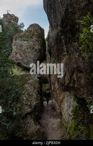 Escursionista passando attraverso Rocks lungo Bear Gulch Trail nel Pinnacles National Park Foto Stock