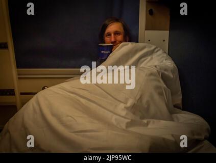 Uomo prima di dormire in un vano di pullman da Praga alla Slovacchia nella notte d'estate Foto Stock