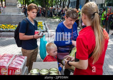 KHARKIV, UCRAINA - 02 agosto 2022: Persone in attesa di lattine di cibo in scatola. Organizzazione di volontariato Caritas Ucraina distribuisce cibo ai bisognosi in Kharkiv Foto Stock