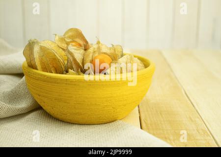 Piccole bacche di fichis gialle su fondo di legno. Frutta Physalis su un tavolo di legno. Bacche di fichis giallo dolce. Spazio di copia Foto Stock