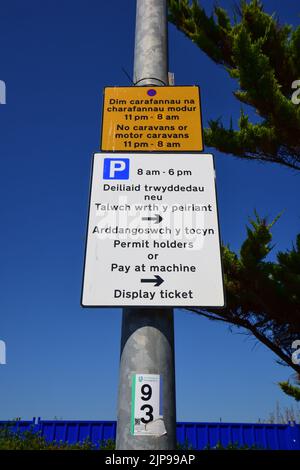 Rhyl, Regno Unito: 11 agosto 2022: Segnaletica bilingue con istruzioni per il parcheggio. Un cartello bilingue spiega le restrizioni per le roulotte e le roulotte a motore. Foto Stock