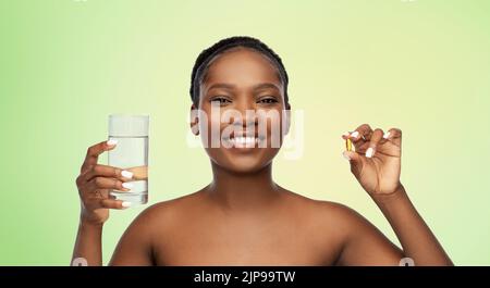 donna africana con olio di fegato di merluzzo e vetro d'acqua Foto Stock