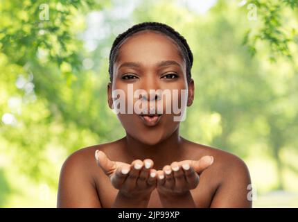 donna africana che soffia qualcosa dalle mani Foto Stock