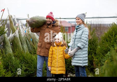 felice famiglia che acquista albero di natale al mercato Foto Stock