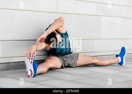 uomo che fa sport e si allunga all'aperto Foto Stock