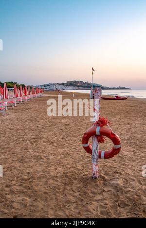 Vieste, Foggia, Italia 26 giugno 2021 Scialara, una spiaggia sabbiosa all'alba e sullo sfondo di rocce calcaree, il centro storico di Vieste e il pizzomunno monolite Foto Stock