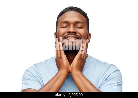 felice uomo afroamericano che tocca la barba Foto Stock