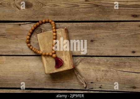 Il rosario di legno giace sulla bibbia su una tavola di legno, la bibbia e la religione, la fede e Dio Foto Stock