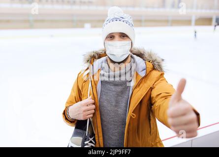 uomo in maschera che mostra i pollici sulla pista di pattinaggio Foto Stock