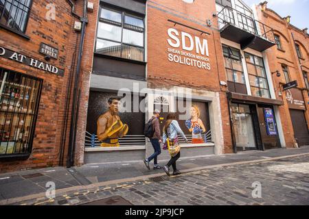 Persone che passavano davanti a un murale su Hill Street a Belfast da Ciaran Gallagher Art, commissionato dal proprietario locale del bar Willie Jack, mostrando i candidati del partito conservatore, Rishi Sunak e Liz Truss come due pugili in procinto di combattere per diventare il primo ministro britannico. Data immagine: Martedì 16 agosto 2022. Foto Stock