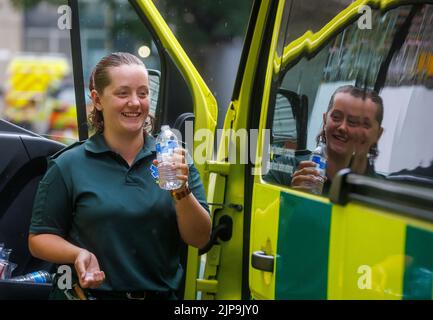 Un operaio di ambulanza prende una pausa durante un turno durante il tempo caldo di estate. Il servizio di ambulanza è sotto pressione con un carico di lavoro aumentato. Foto Stock