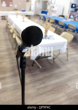 Microfono su un supporto in una sala banchetti con tavoli e sedie per una festa Foto Stock