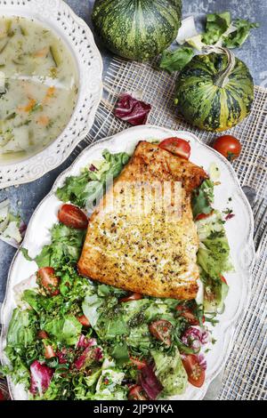 Salmone speziato con erbe, un piatto di zuppa di verdure e un'insalata fresca. Cibo sano Foto Stock