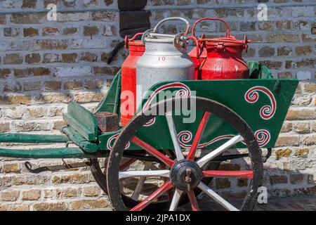 Carrello a mano antico caricato con quattro vecchie churns di latte di metallo / lattine di latte Foto Stock