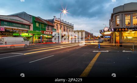 Auto che attraversano i negozi Balmoral su Dominion Road, una popolare zona di negozi e ristoranti Foto Stock