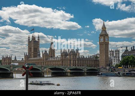 Londra, Regno Unito - 4 luglio 2022: House of Lords, Westminster Palace, hall e ponte, e Big ben sotto il paesaggio azzurro del Tamigi visto da op Foto Stock